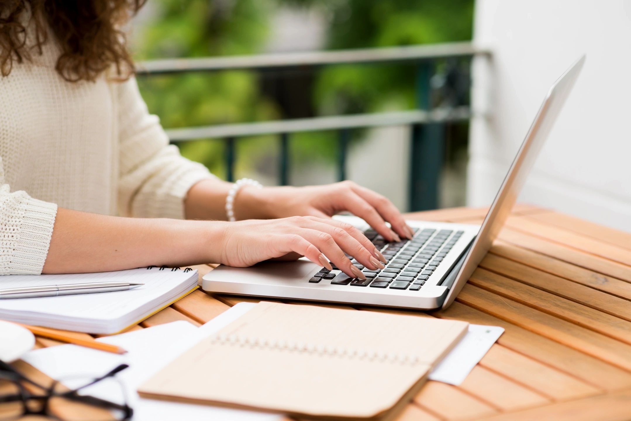 Person typing on a laptop at a wooden desk