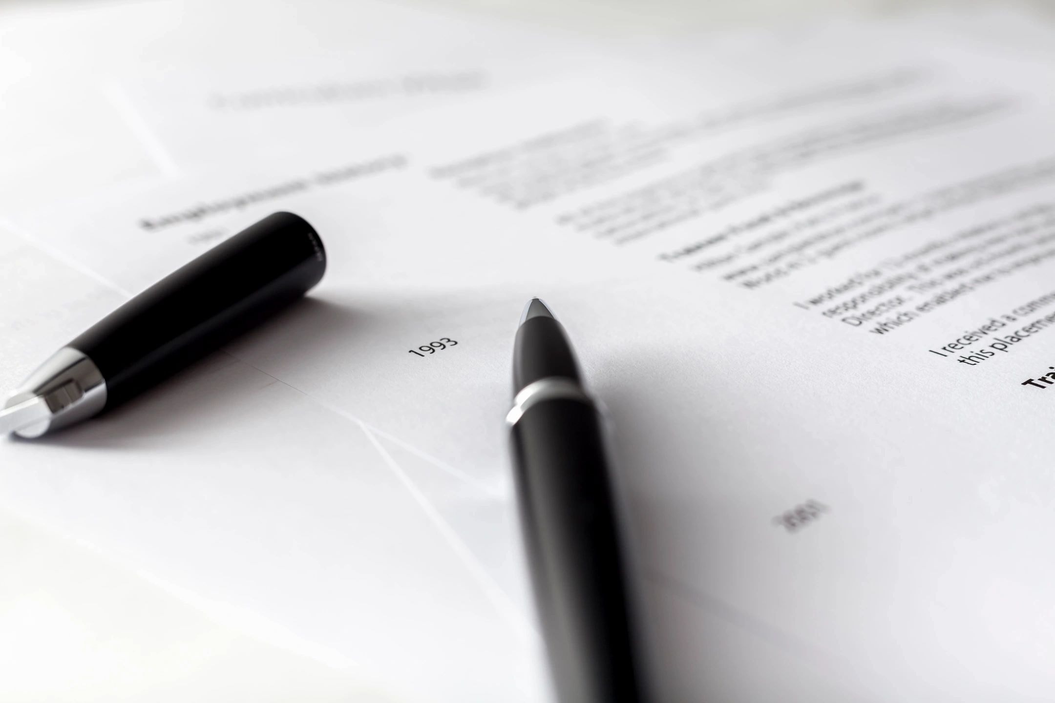 Fountain pen resting on printed resume documents